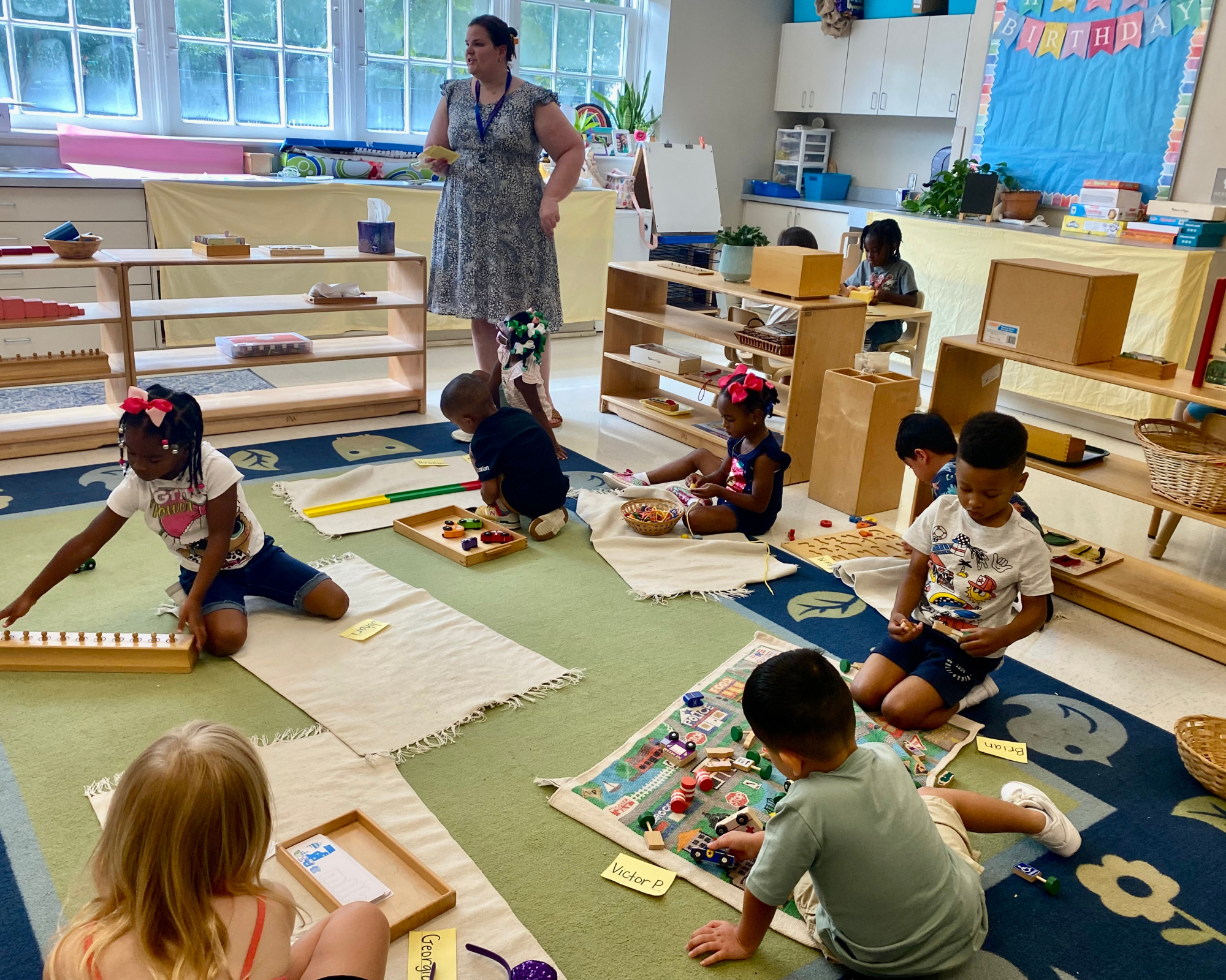 Children engaging with Montessori materials on classroom work mats